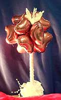 This 18 inch tall centerpiece displays a sphere-shaped cluster of mauve heart balloons on a cream-colored stand topped by a cream-colored dove figurine